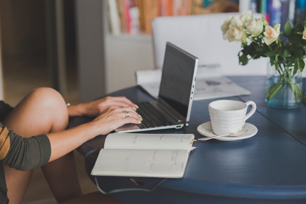 pexels-photo-4012966-1 Female freelancer using laptop with coffee at home office desk, surrounded by roses and a planner.